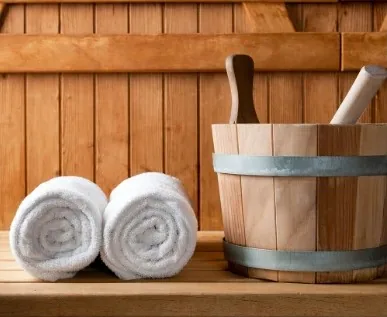 Rolled white towels beside a wooden bath bucket